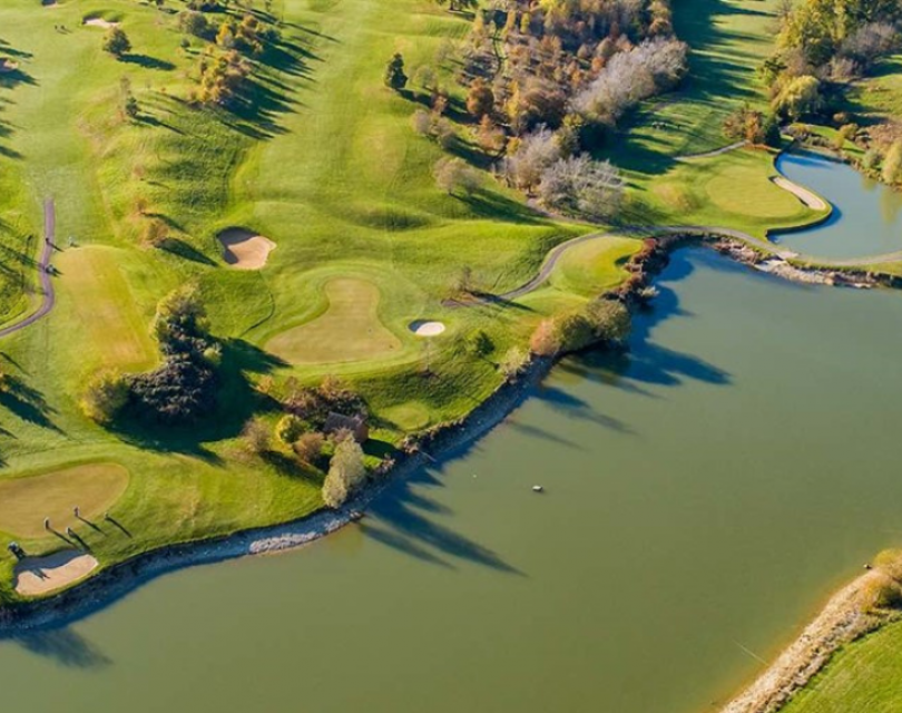 birds eye view over golf club with lake in foreground